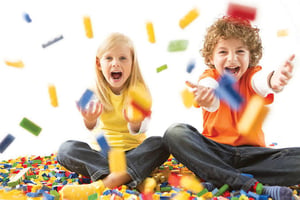 A young boy and girl throwing building bricks in the air